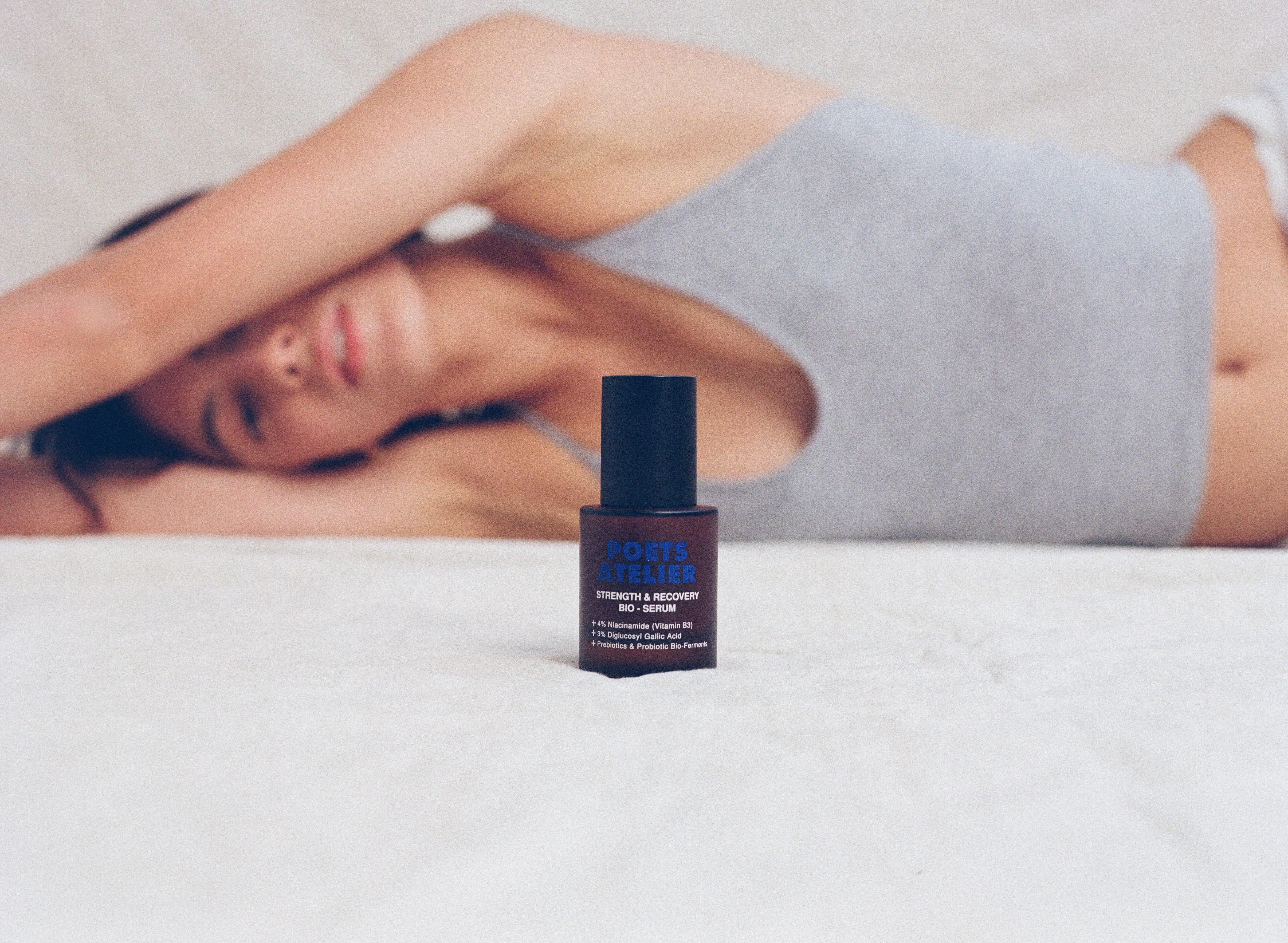 Face serum on bed with woman in the bakground